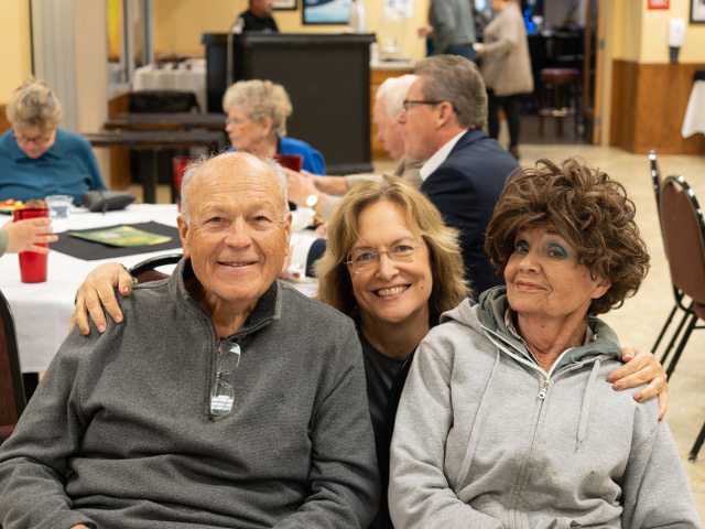 Long-time supporters of Crest View are happy to be part of the celebration! Description: A group of 3, two women and one man. All three are looking at the camera and smiling.