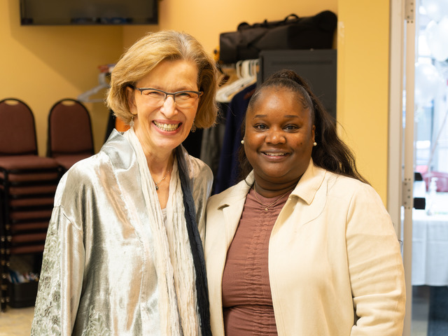Shirley Barnes and Kiara are excited to be a part of the celebration Description: Two women side by side smile towards the camera. The woman on the left has short blond hair and glasses. The woman on the right has long black/brown hair and is wearing a cream cardigan.